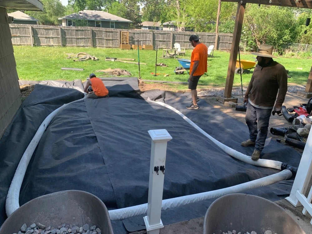 Drainage Fabric and Pipe Installation — Backyard Project John's Pro Care crew laying landscape fabric and drain pipe across large backyard drainage system