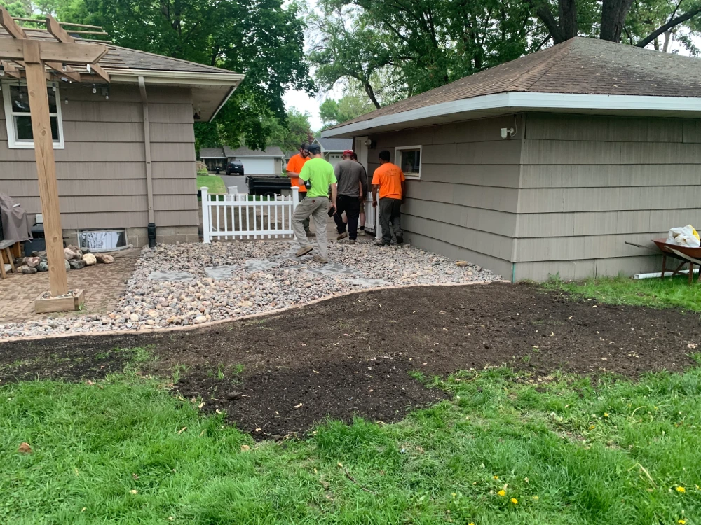Drainage and Gravel Installation Nearing Completion John's Pro Care crew finishing gravel drainage installation alongside residential garage and patio