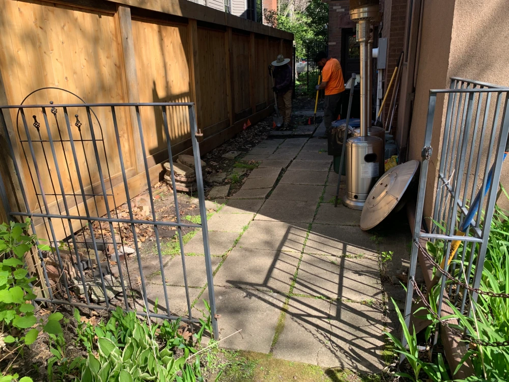 French Drain Excavation in Progress — John’s Pro Care Crew John's Pro Care crew excavating trench for french drain installation along residential fence line