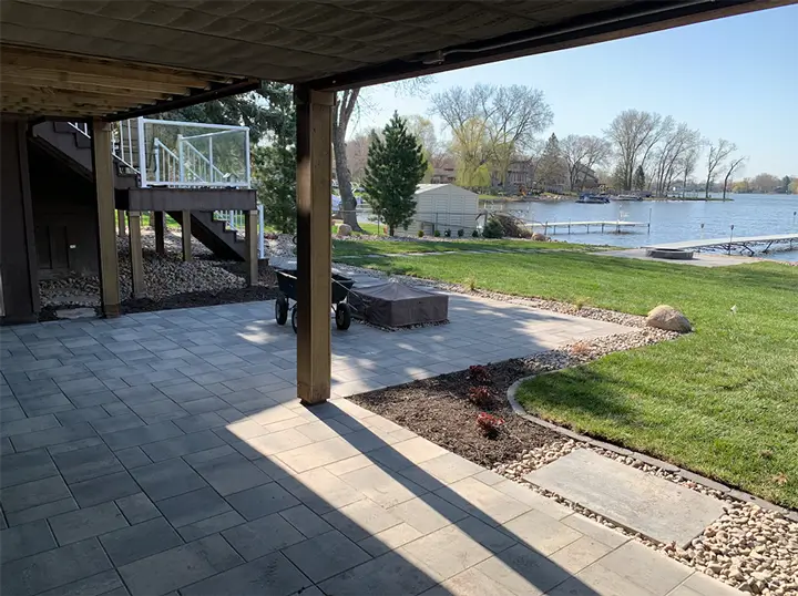 John's ProCare paver patio with gray stone pavers beside a landscaped backyard and lake